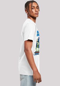 White cotton t-shirt featuring a graphic of a cartoon character on books. Short sleeves, crew neck, relaxed fit, smooth texture.