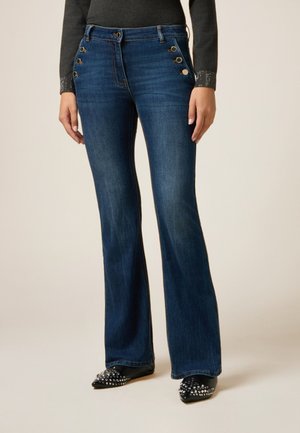 Donkerblauwe flared jeans met gouden knoopaccenten op de voorzakken. Het materiaal heeft een zachte textuur, geschikt voor casual kleding.