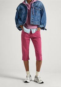 Jeansjacka, rosa hoodie med dragkedja, ljusblå skjorta, rosa capribyxor, vita strumpor och grå sneakers med silverdetaljer.