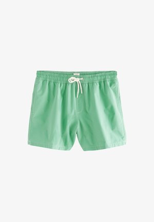 Bañador verde de tejido ligero. Cuenta con una cintura elástica con cordón, bolsillos laterales y costuras en contraste.