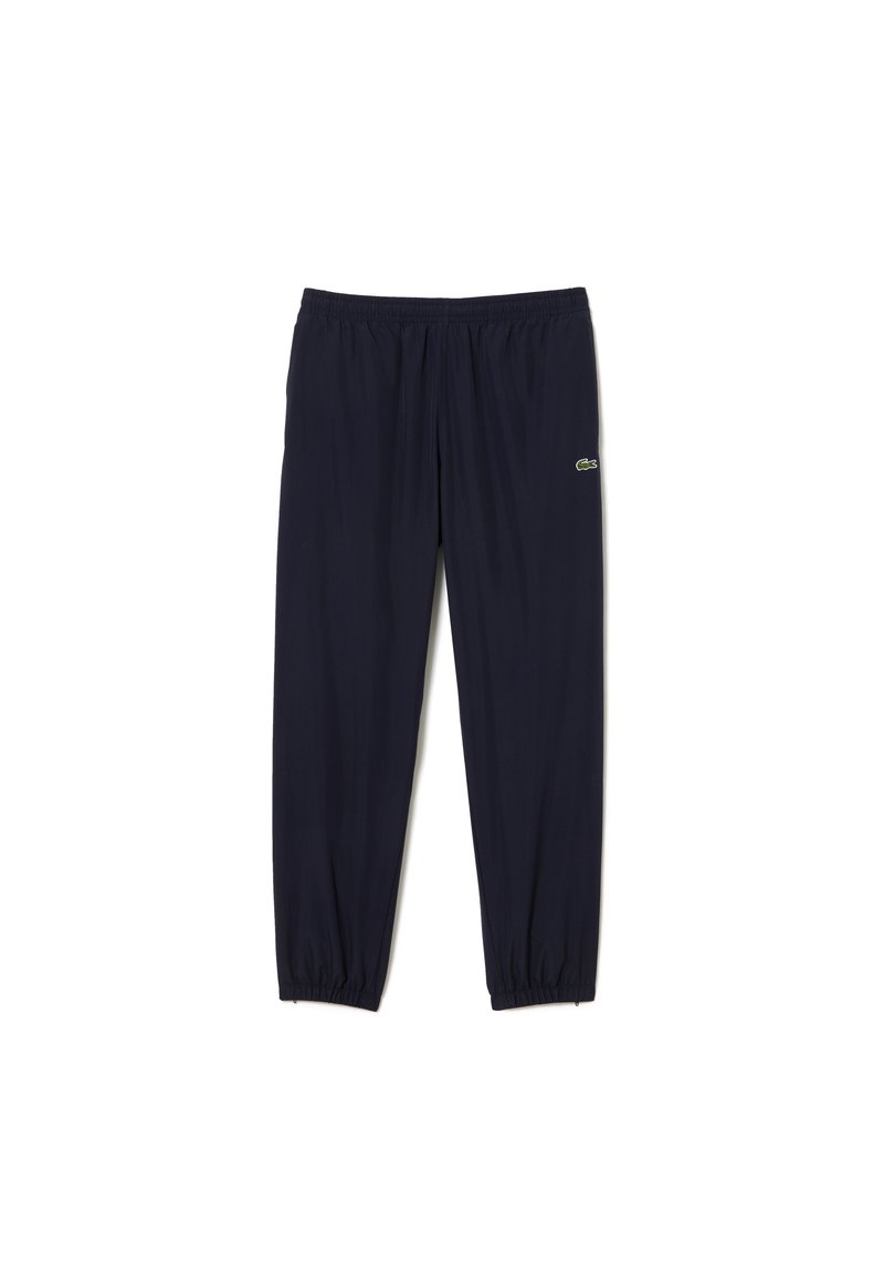 Pantalon de survêtement bleu marine avec taille élastique et poignets, arborant un petit logo crocodile vert sur la cuisse droite.