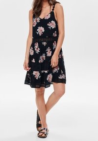 Blumenkleid aus dunkelblauem Stoff mit pinken Rosen, dünnen Trägern, taillierter Passform und einem ausgestellten Rock mit Spitzenbesatz am Saum.