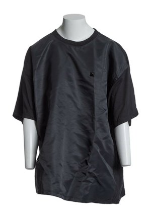 Czarny oversize t-shirt z krótkim rękawem i błyszczącym panelem materiału z przodu, prezentowany na białym manekinie bez głowy.