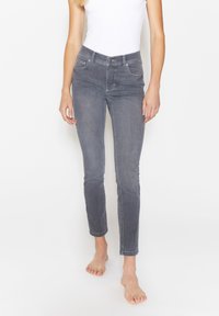 Eng anliegende graue Jeans aus Denim mit mittelhohem Bund, fünf Taschen und dezenten Nähten. Knöchellanges Design mit glatter Textur.