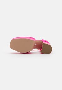 Sandal con tacco alto rosa con tomaia liscia e lucida e suola a piattaforma. Base piatta e texturizzata e cinturino regolabile alla caviglia.