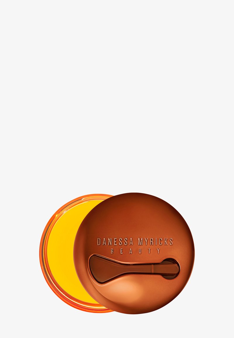 Rund, bronsebeholder med preget tekst og buet lokk; livlig gul innvendig; inkluderer et lite påføringsverktøy.