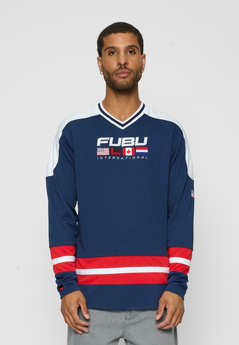 Tricou cu mânecă lungă de culoare bleumarin, cu dungi roșii și albe la tiv și la mâneci, având logo-ul "FUBU INTERNATIONAL" și multiple grafice cu steaguri.