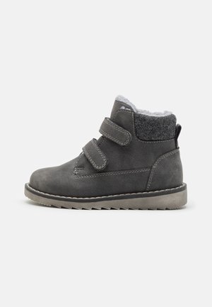 Bottine en daim gris avec deux bandelettes Velcro ajustables, doublure en polaire grise douce et semelle en caoutchouc robuste avec un motif en zigzag.