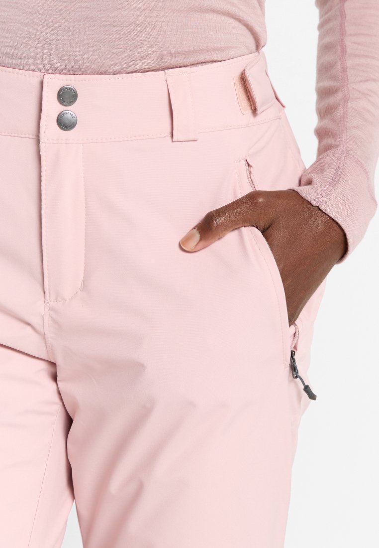 Jasnoróżowe spodnie zewnętrzne o gładkiej fakturze, z dwiema przednimi kieszeniami, okrągłymi srebrnymi guzikami i kieszenią na zamek po boku.