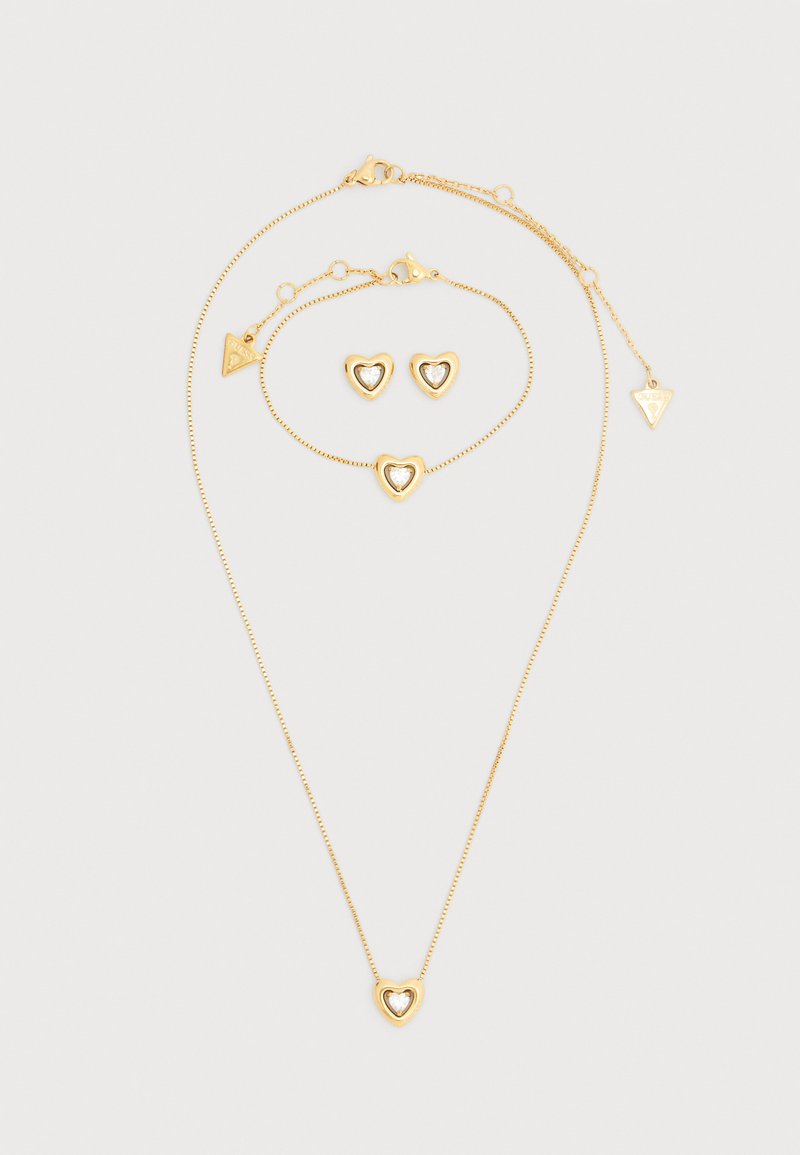 Σετ κοσμημάτων σε χρυσό τόνο με κολιέ με μενταγιόν σε σχήμα καρδιάς, βραχιόλι που ταιριάζει και σκουλαρίκια καρφίτσες με μοτίβα καρδιάς. Ομαλή υφή.