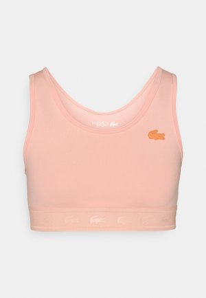 Ružová športová podprsenka vyrobená z mäkkého materiálu, s hlbokým výstrihom a viditeľným švom. Obsahuje vyšívané logo vpredu a logo okolo pásu.