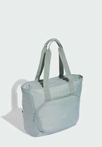 Bolso grande de mano de color verde claro hecho de tela resistente, con dos asas sólidas y un bolsillo delantero con cremallera que muestra un logo sutil.