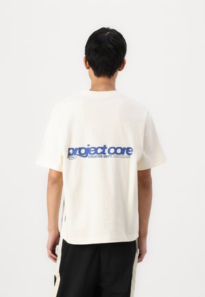 Ivory short-sleeve T-shirt featuring large blue text "project core" and small logo print on the back, with a relaxed fit and side slits.