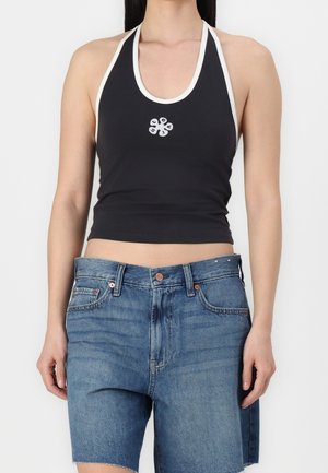 Top noir à bretelles avec des finitions blanches, présentant un motif floral sur le devant ; associé à un short en denim bleu, avec une finition brut.