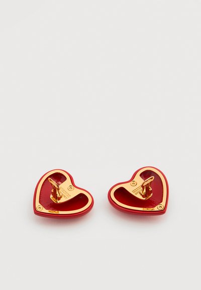 Boutons de manchette en forme de cœur rouges et dorés avec fermoirs à bascule sur fond blanc.