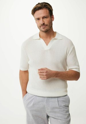White short-sleeve knit polo with a V-neck and textured pattern, paired with light gray striped trousers. Casual design, breathable material.