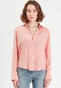 Chemise à boutons rayée rose avec des manches longues et amples et un col. Tissu léger avec une coupe décontractée ; comporte des boutons blancs sur le devant.