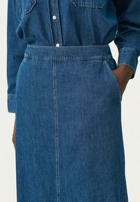 Denim haljina tamnoplave boje, s dugmadi sprijeda, dugim rukavima i pojasom u struku, bočnim dzepovima i ravnim krojem.