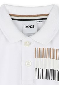 Witte polo shirt met een klassieke kraag, knoopsluiting en een kleurrijk gestreept patroon in beige, wit en zwart aan de zijkant.