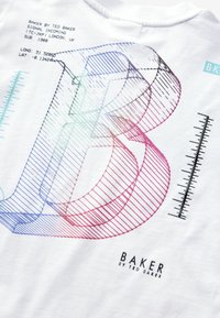 Bílý bavlněný tričko s velkým vícebarevným geometrickým grafickým prvkem "B". Obsahuje textové detaily a minimalistický design pravítka.