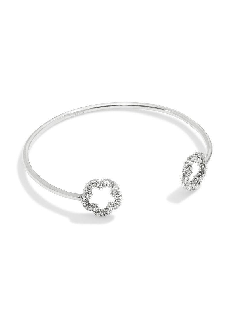 Pulsera abierta de plata con extremos en forma de trébol adornados con cristales, sobre un fondo blanco.