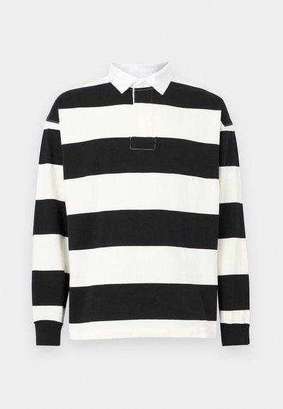 Μακρυμάνικο ρούχο ράγκμπι με φαρδιές οριζόντιες μαύρες και λευκές ρίγες και λευκό γιακά με κουμπιά, εμφανιζόμενο σε απλό φόντο.