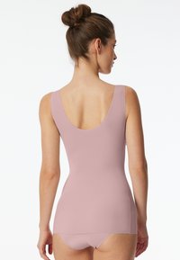 Light pink tank top with a scooped back and thin straps, featuring a smooth texture and a fitted design, paired with matching brief bottoms.