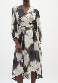 Rochie tip wrap în negru, Crem și gri; prezintă un design plisat, mâneci lungi, talie legată și o linie de bază fluidă cu un model floral subtil.