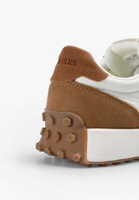 Brązowe zamszowe i białe tekstylne sneakersy z masywną brązową gumową podeszwą z heksagonalnymi wstawkami. Obszycia na cholewce.