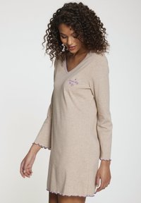 Vestido beige de cuello en V con mangas largas, ribete morado en las mangas y el dobladillo, y "sueña en grande" bordado en morado en la parte delantera.