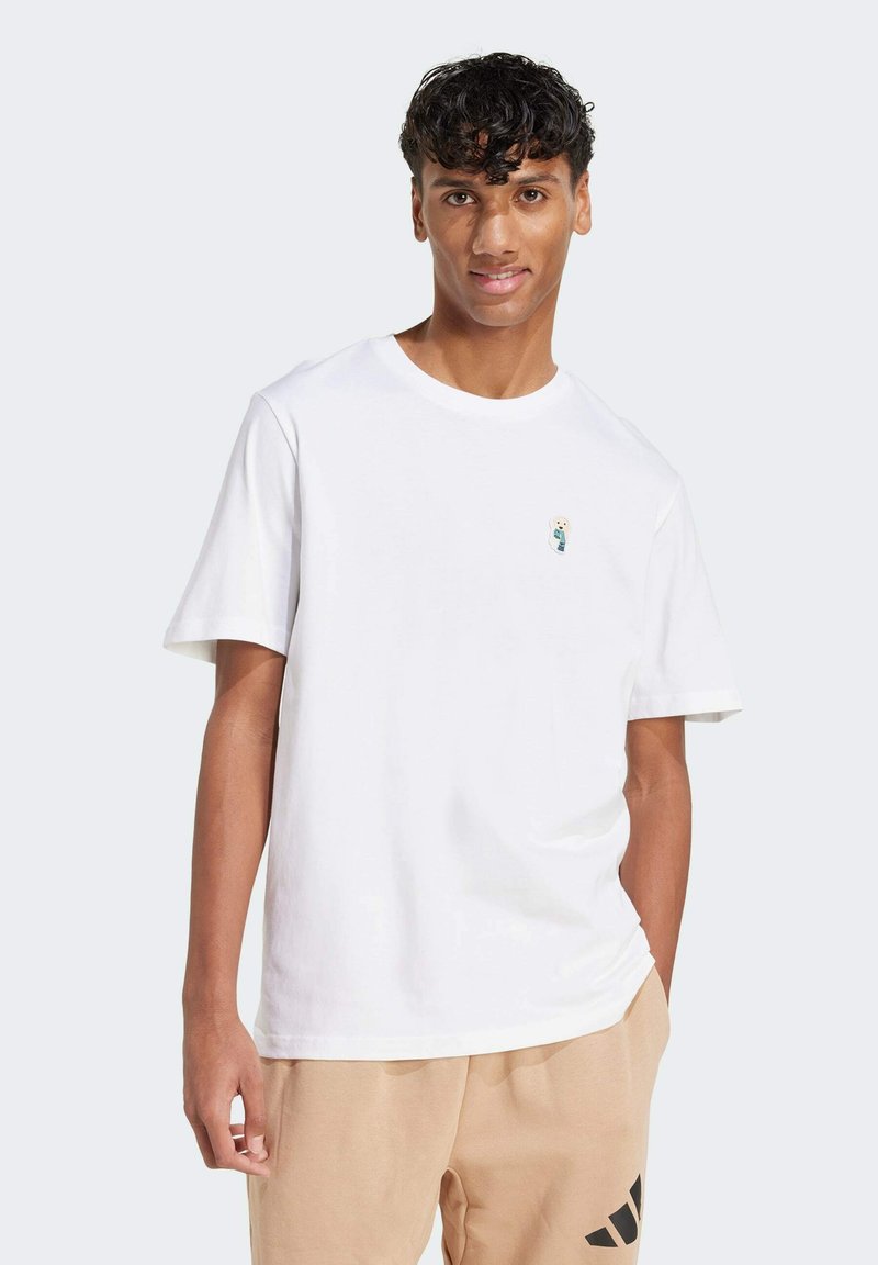 Biela bavlnená tričko s krátkymi rukávmi a okrúhlym výstrihom. Obsahuje malú, detailne vykreslenú grafiku na oblasti ľavého hrudníka.