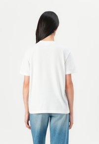 White short-sleeve t-shirt in soft cotton, featuring a simple crew neck, relaxed fit, and smooth texture. Back view shows no graphics.