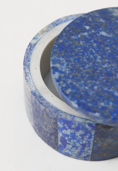 Rund behållare av blå lapis lazuli med en slät, glänsande yta. Har ett matchande lock och ett kontrasterande inre material.