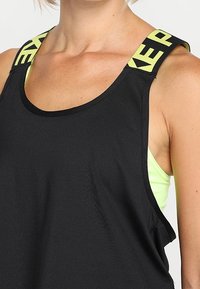 Canotta sportiva nera con spalline larghe e lettering giallo neon. Tessuto leggero con vestibilità comoda e scollatura arrotondata.