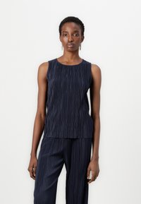 Navy pleated sleeveless top, featuring a round neckline and textured fabric, with a soft drape extending to the waist. Coordinating pants visible.