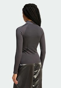 Tmavosivý dlhý rukáv s vysokým golierom, textúrovanou látkou a priliehavým strihom v kombinácii s lesklými čiernymi nohavicami.