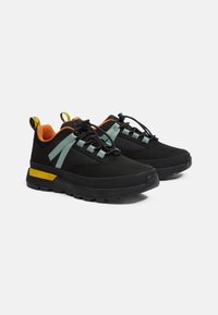 Scarpe da ginnastica nere con suola in gomma testurizzata, dettagli verde menta e fodera arancione brillante. Le caratteristiche includono un colletto imbottito e lacci regolabili.