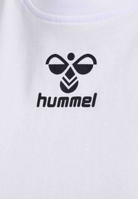 Biała bawełniana koszulka z czarnym logo Hummel, z stylizowanym wzorem pszczoły nad nazwą marki napisaną małymi literami.
