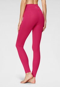 Leggings rosa realizzati in materiale elasticizzato con una vita alta, caratterizzati da una superficie liscia e senza motivi visibili o dettagli in metallo.