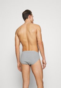 Graue Baumwollslips mit glatter Textur, die einen mittelhohen Bund und ein enganliegendes Design aufweisen. Die Rückansicht zeigt eine minimale Bedeckung.