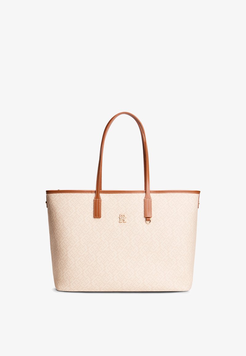Μπεζ τσάντα ώμου με σώμα από υφασμάτινο με μοτίβο, καφέ δερμάτινες χειρολαβές και περίγραμμα, με χρυσό λογότυπο στο μπροστινό μέρος.