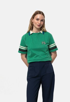 T-shirt en coton vert avec un col rayé blanc et bleu, des rayures blanches sur les manches, et le numéro "75" en noir sur le devant.