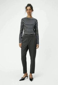 Gestreepte lange mouwtop in grijs en zwart; gecombineerd met donkergrijze slim-fit broek; model draagt puntige zwarte hakken; gladde stofstructuur.