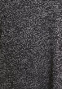 Mörkgrått stickat tyg med en subtil struktur där ljusare grå trådar är vävda, vilket skapar ett melerat mönster.