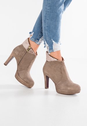 Bottines en suède beige avec un bout rond, un talon aiguille de 10 cm de hauteur et un col texturé de couleur beige clair avec des clous décoratifs.