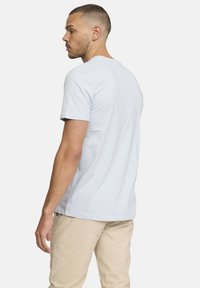 T-shirt en coton bleu clair à manches courtes et col rond, avec une texture lisse et un design simple, présenté en vue de côté.