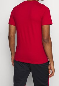 Rode t-shirt met korte mouwen en ronde hals. Gladde katoenstof, getailleerd ontwerp, effen textuur, zonder patronen of accenten.