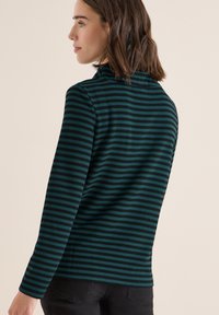 Camicia a maniche lunghe in tessuto testurizzato con righe orizzontali blu scuro e nere. Collo semplice e design aderente sul retro.