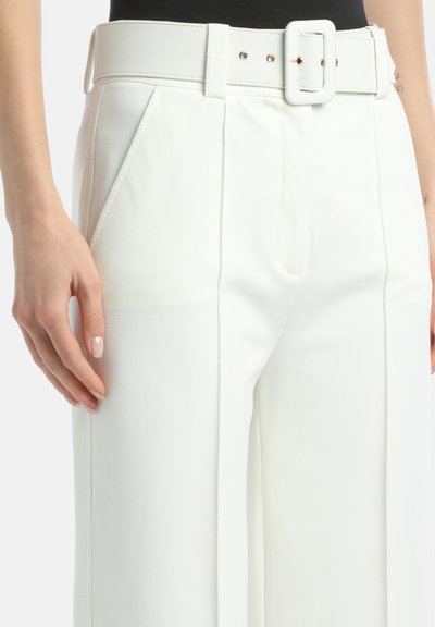 White tailored pants with a wide waistband and belt featuring a square buckle. Soft texture and sharp pleats detail on the front.