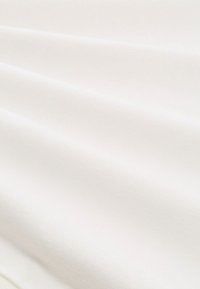 Zachte, witte stof met een gladde textuur, voorzien van subtiele plooien en een egale oppervlakte. Ideaal voor kleding of bekleding.